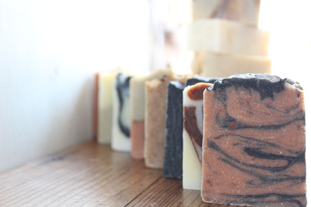 Une rangée de savons artisanaux posés sur une étagère en bois